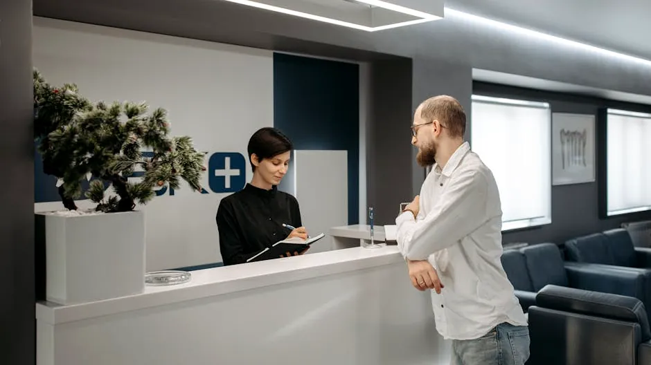 A man consults a receptionist in a modern clinic setting with contemporary design.