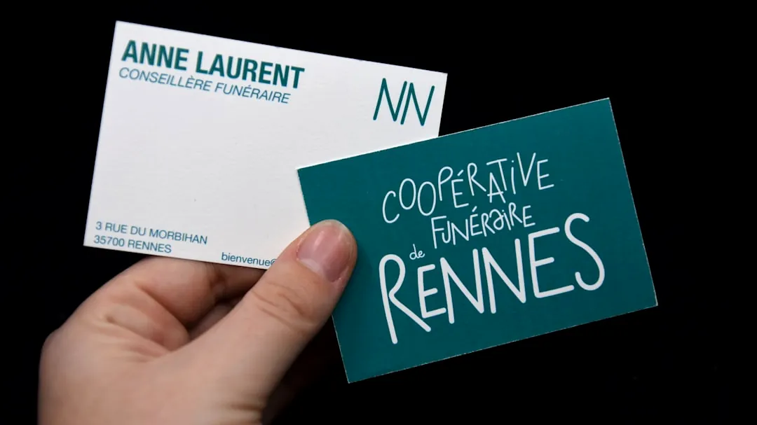 Hand holds two business cards against black background