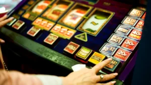 Hands pressing buttons on a colorful slot machine.