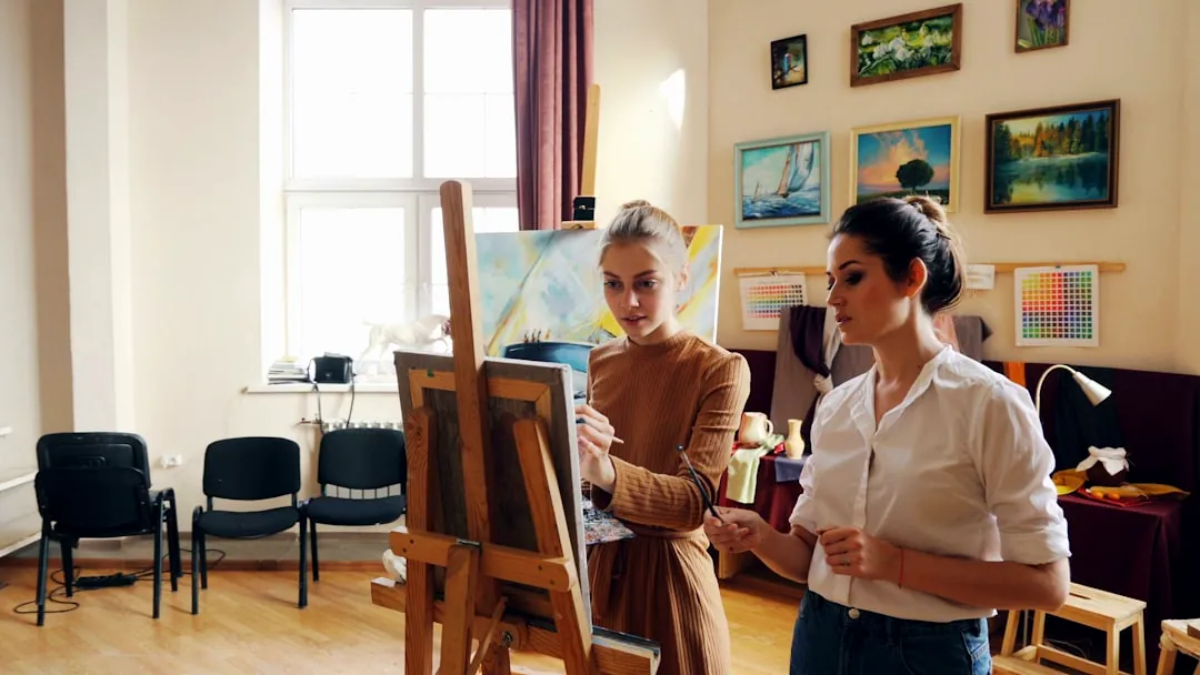Two women paint together in an art studio.