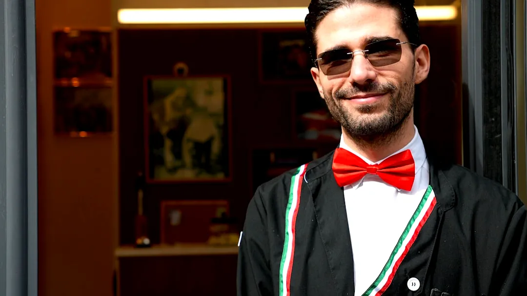 Man in sunglasses wearing a red bowtie and jacket.