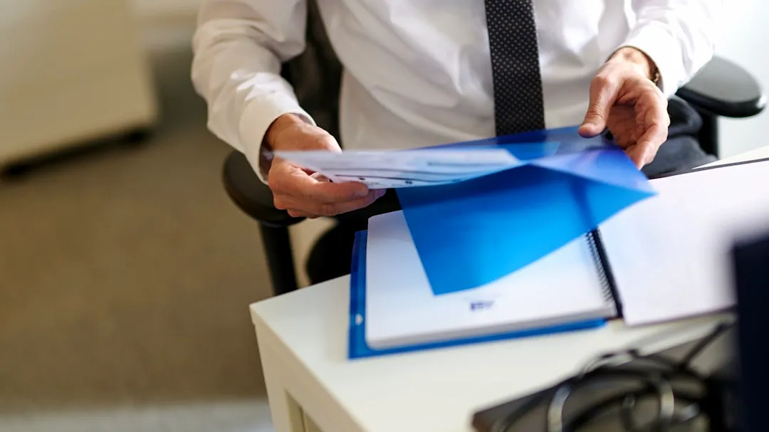 a man in a white shirt and tie holding a folder